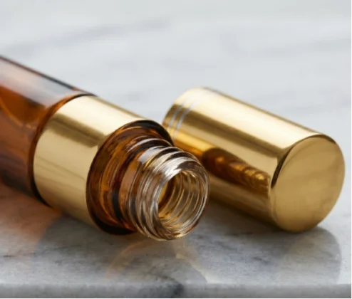 Close-up of amber perfume bottle with gold cap removed.