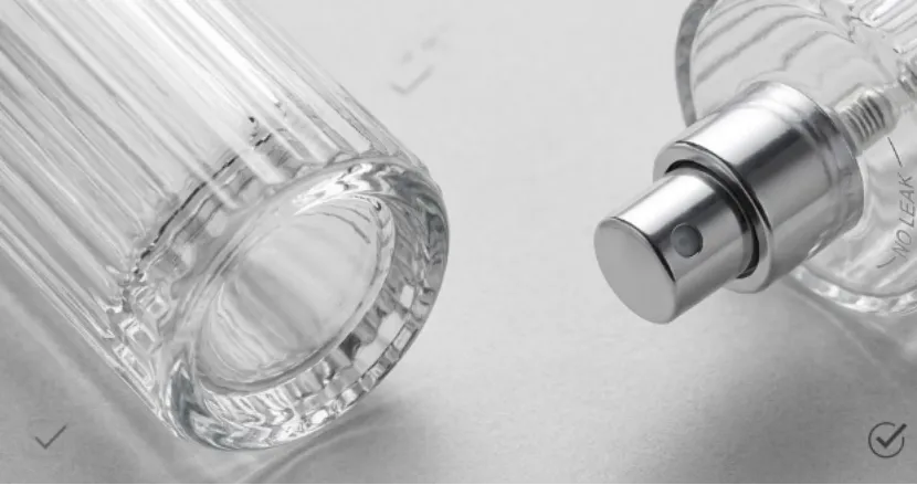 Detailed macro close-up of a fluted glass bottle base and a silver sprayer nozzle.