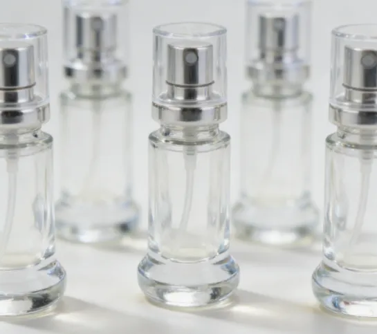 Group of five small clear glass perfume spray vials on a white surface.