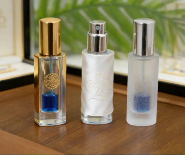 Three filled perfume bottles on wood, including gold, satin-wrapped, and frosted designs.